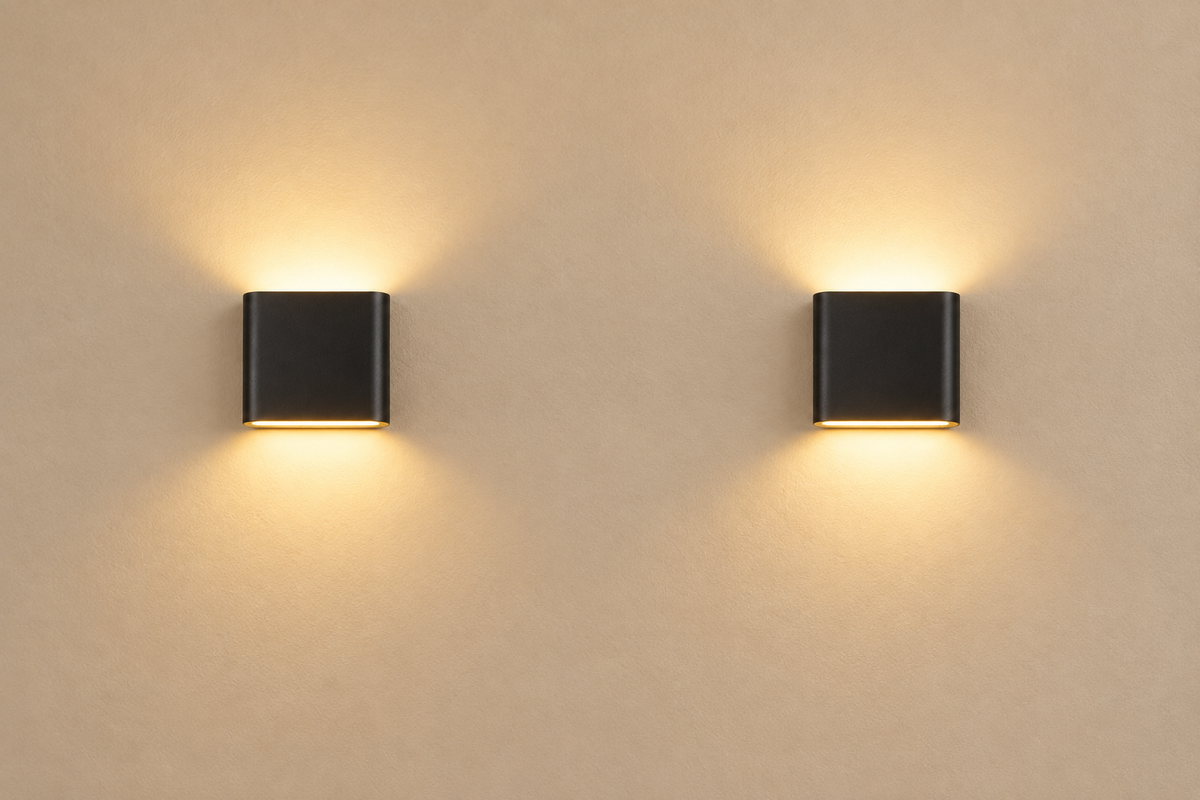 A pair of matte-black Duo Up/Down Wall Lights on a warm-beige plaster wall with soft warm white glow