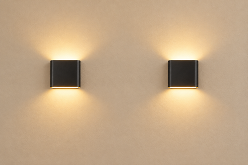 A pair of matte-black Duo Up/Down Wall Lights on a warm-beige plaster wall with soft warm white glow
